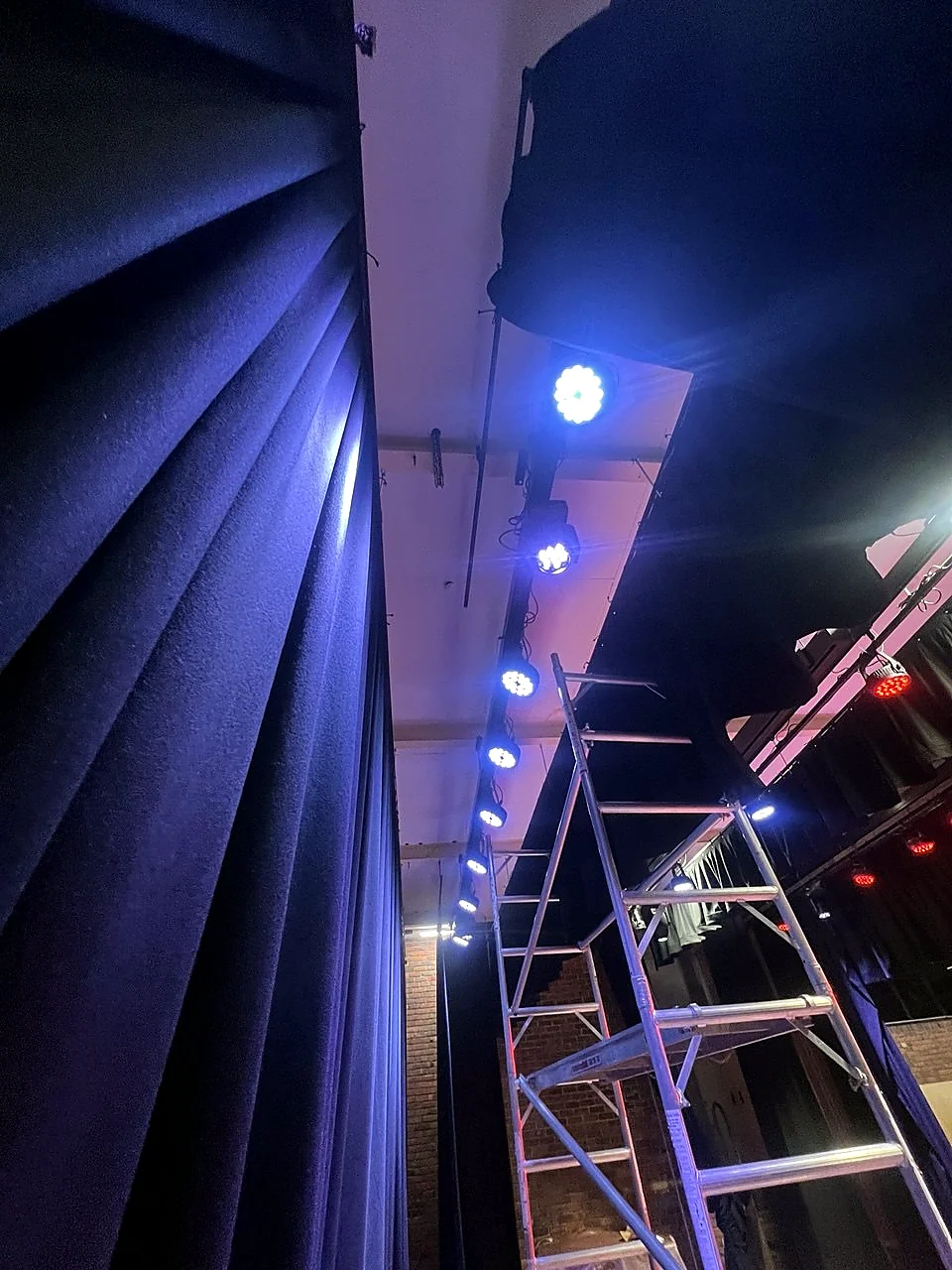 Blue theatre lighting over stage curtains